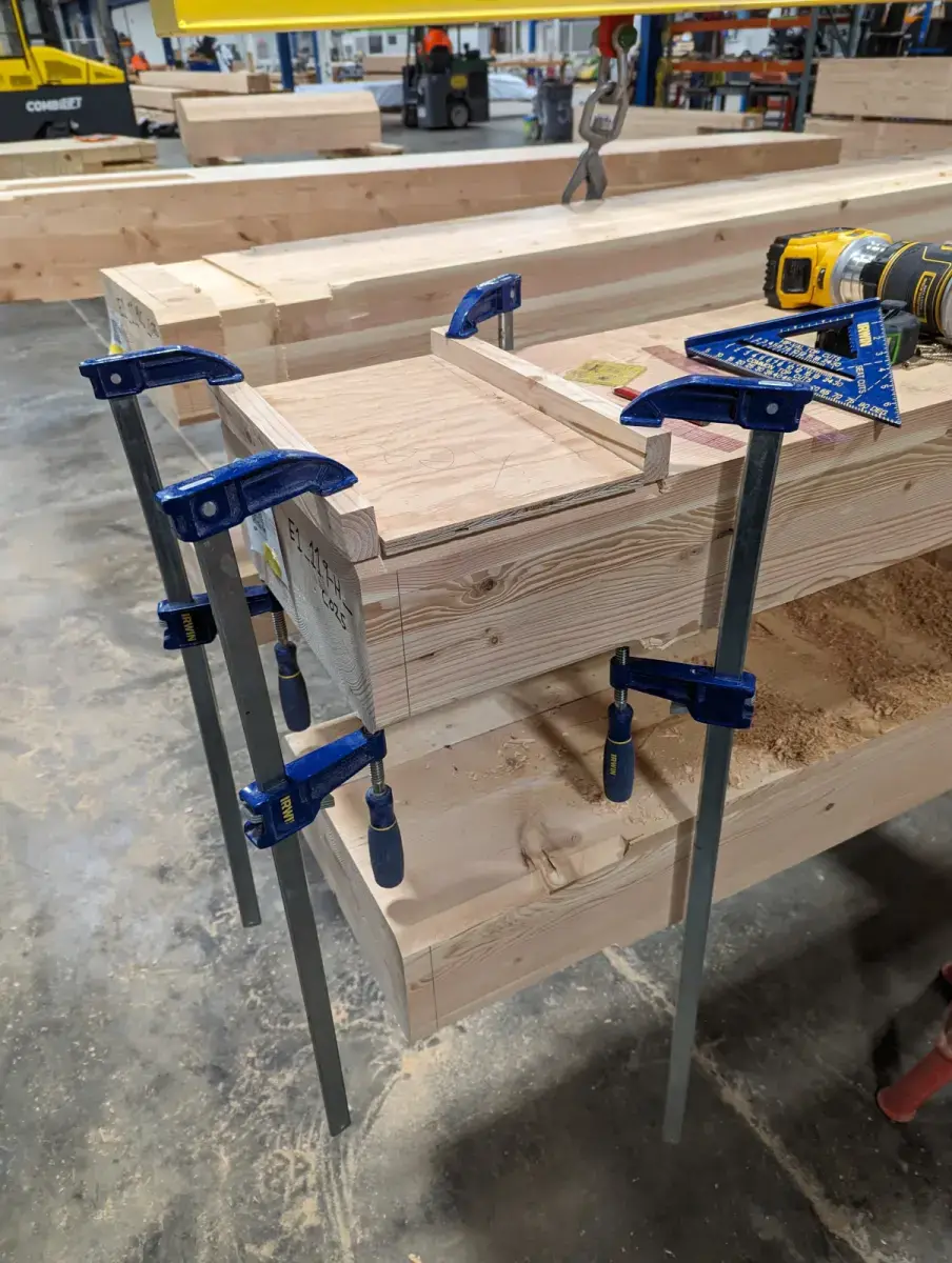 Prior naive routing guide secured to timber beam. Two small straight edges laid across the column, each secured with a bar clamp at each end
